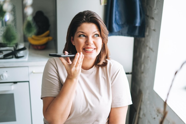 Linda jovem morena feliz com corpo de tamanho positivo falando pelo celular em casa