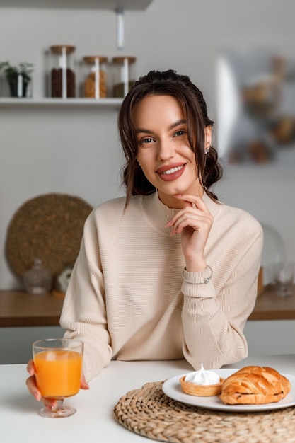 Foto linda jovem morena na cozinha com um suéter com limão lindo sorriso