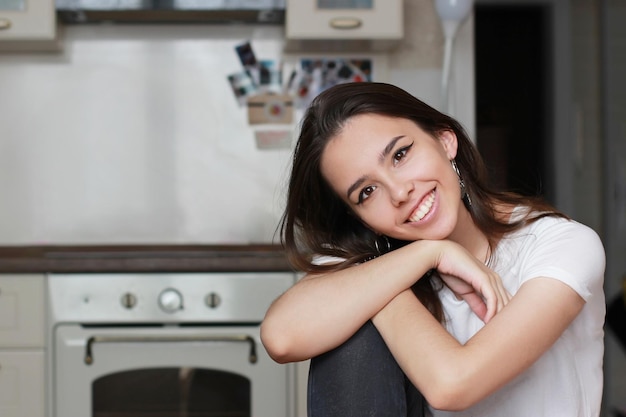 Linda jovem morena olha diretamente para a câmera e sorri