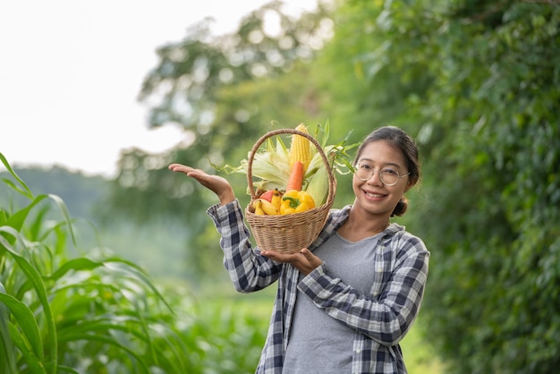 Linda jovem morena Retrato Famer Mulher segurando legumes na cesta de bambu em verde