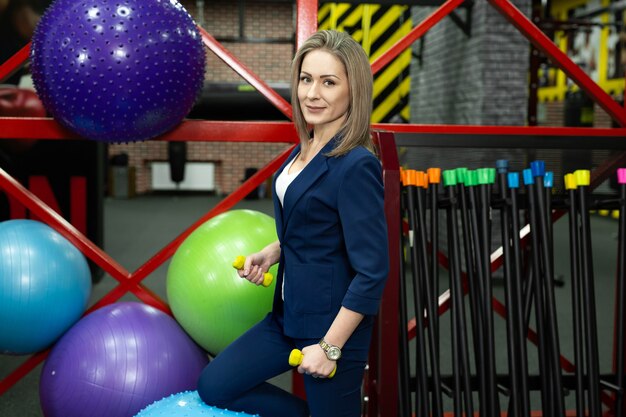 Linda jovem mulher de negócios com halteres no ginásio.