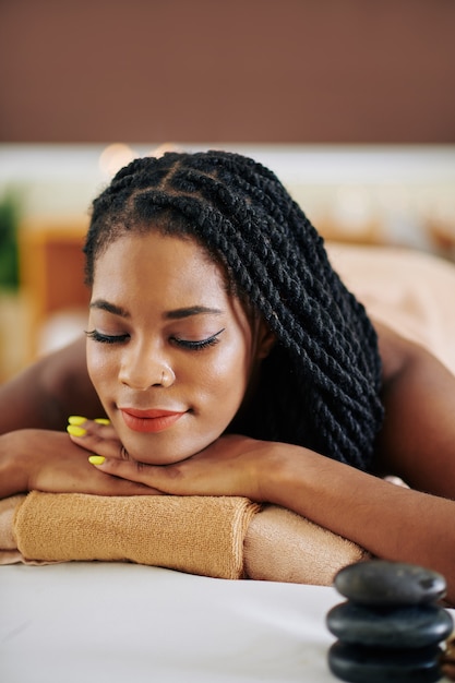 Linda jovem negra com dreadlocks relaxando na cama em um salão de beleza após realizar um procedimento de emagrecimento