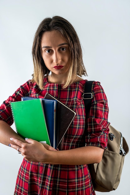 Linda jovem professora em pé com livros nas mãos isoladas em fundo liso