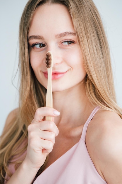 Linda jovem segurando uma escova de dentes de bambu útil. o conceito de um estilo de vida saudável, respeito pelo meio ambiente e desperdício zero. tonificação.