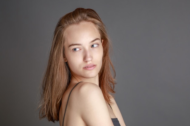 Linda jovem sorridente com conceito de beleza natural de rosto de pele perfeito isolado no fundo do estúdio