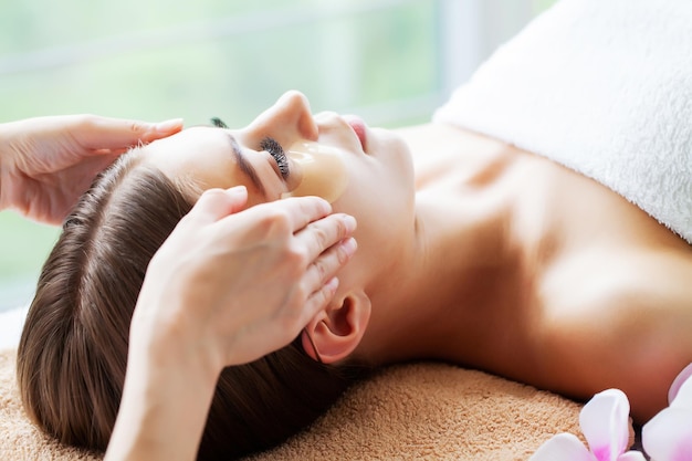 Linda jovem tendo uma massagem facial relaxante no salão spa.