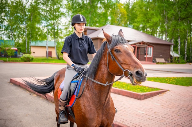 Linda jovem usando capacete montando seu cavalo marrom
