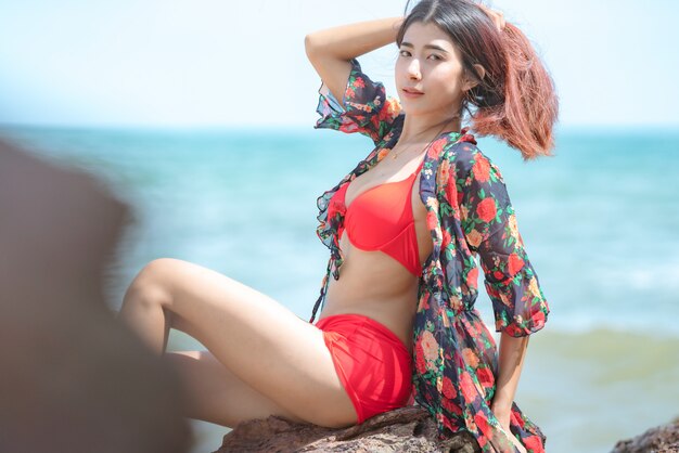 Linda joven asiática en bikini feliz en la hermosa playa en vacaciones de verano en Tailandia