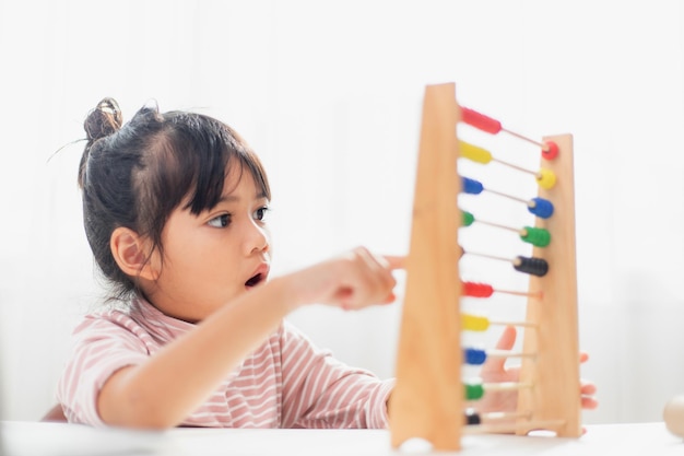 Una linda joven asiática está usando el ábaco con cuentas de colores para aprender a contar en casa