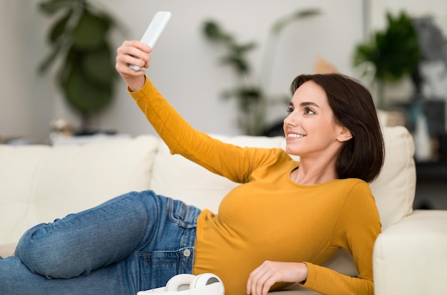 Linda joven bloguera tomando selfie en casa