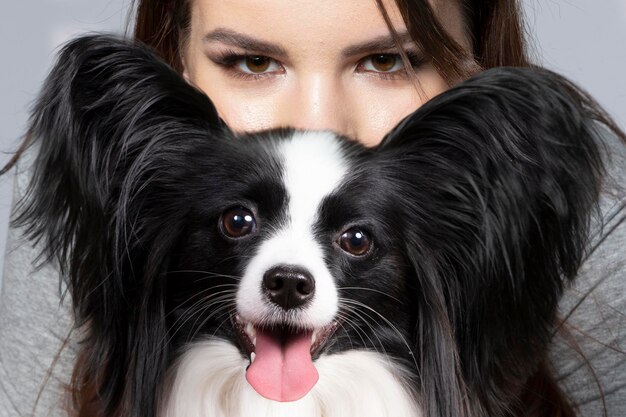 Una linda joven está abrazando a su cachorro papillon