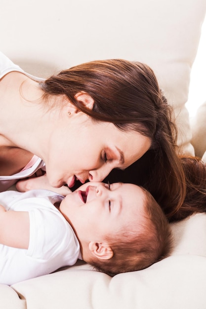 La linda joven madre besa suavemente a su pequeño hijo.