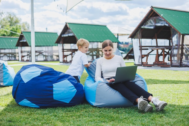 Linda joven madre e hijo mirando la computadora portátil Familia feliz madre e hijo están descansando en el parque Una mujer con licencia de maternidad