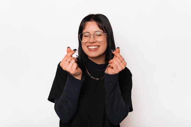 Linda joven mujer sonriente se muestra con ambas manos en forma de corazón coreano