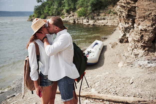 Foto linda joven y pareja en el río. un hombre y una mujer con mochilas viajan en bote. concepto de verano viajero