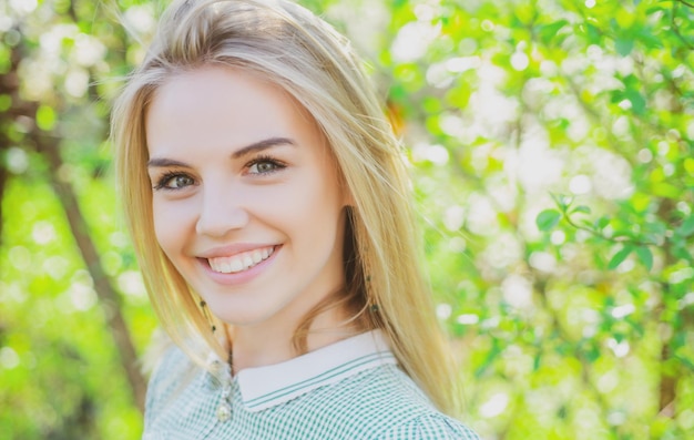 Linda joven primavera mujer niña con fondo de flor Sonriente mujer de verano en el parque Estado de ánimo optimista