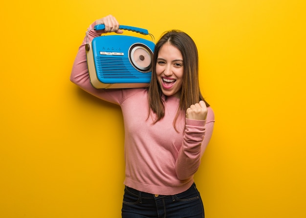 Linda joven sosteniendo una radio vintage sorprendida y consternada