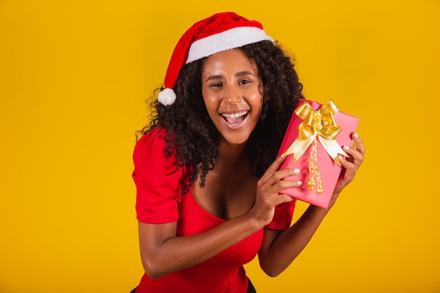 Linda jovencita afro sosteniendo un regalo de Navidad.