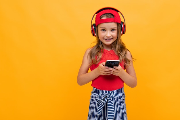 Linda jovencita encantadora con auriculares rojos sobre un fondo amarillo