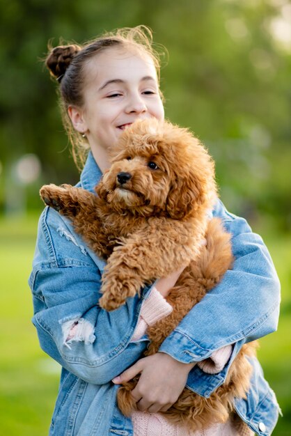 Una linda jovencita paseando con un perro caniche toy. Infancia. Mascotas.