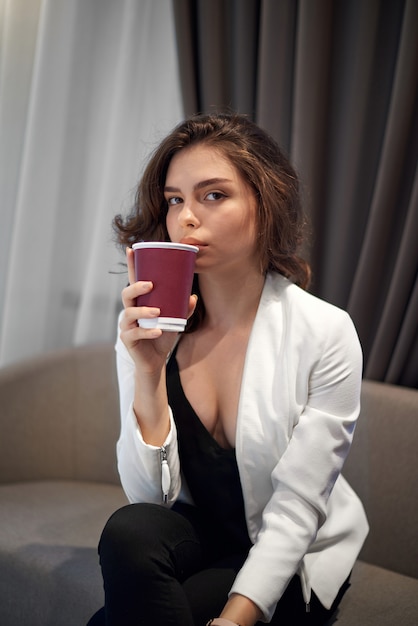 Linda jovencita tomando café en la cafetería