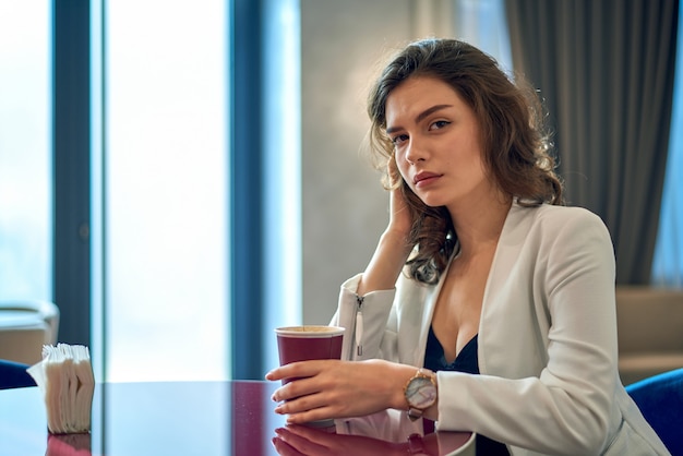 Linda jovencita tomando café en la cafetería