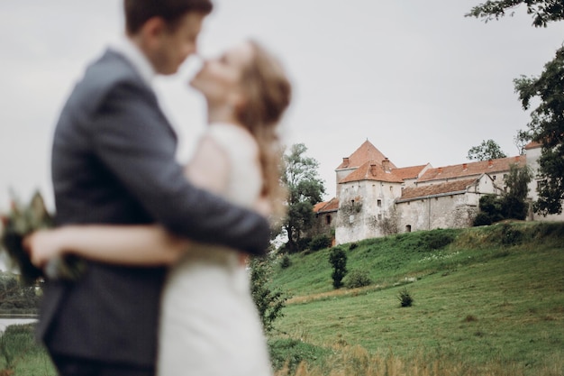 Linda linda noiva e noivo andando no parque ensolarado e beijando casal de noivos felizes abraçando no jardim verde no velho castelo foco na construção do conceito de fuga