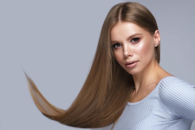 Linda loira com um cabelo perfeitamente liso e maquiagem clássica Rosto e cabelo de beleza