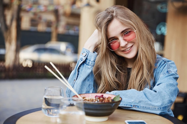 Foto linda loira comendo no restaurante asiático ao ar livre enj