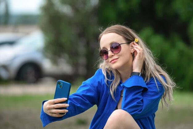 linda loira de camisa azul faz uma selfie na câmera do telefone dela