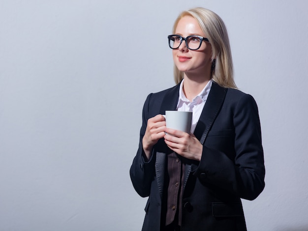 Linda loira empresária de terno com uma xícara de café