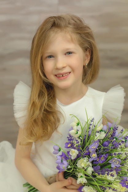 linda loira feliz em um vestido branco com flores nas mãos