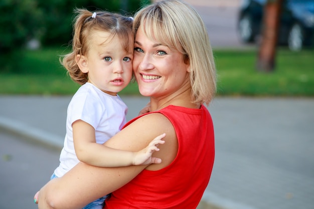 Linda loira mãe em uma camiseta vermelha com sua filha. retrato de grupo