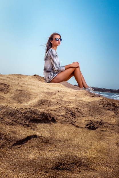 Linda loira sexy em traje de banho posando na praia na areia