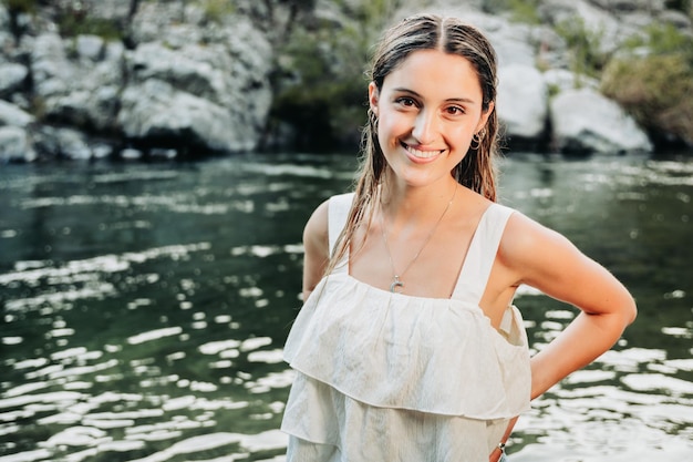 Linda loira, usando uma camiseta branca em um espaço natural, à beira do rio.