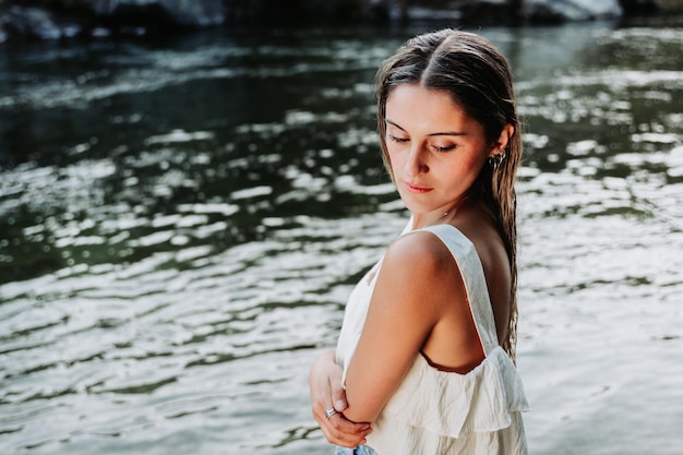 Linda loira, usando uma camiseta branca em um espaço natural, à beira do rio.