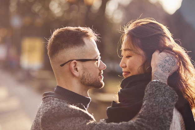 Linda luz do sol. Casal feliz multirracial juntos ao ar livre na cidade.