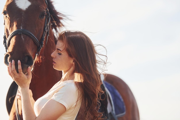 Linda luz do sol Jovem de pé com seu cavalo no campo de agricultura durante o dia