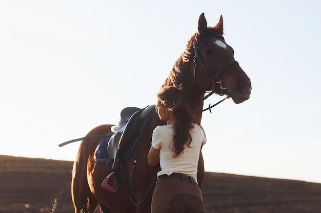 Linda luz do sol Jovem de pé com seu cavalo no campo de agricultura durante o dia