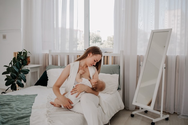 Linda mãe amamentando sua filha bebê na cama do quarto