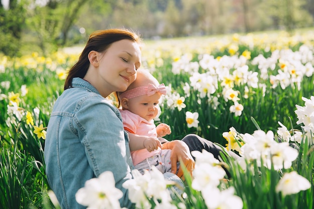Linda mãe amorosa e menina no campo de flores de narcisos na primavera Jovem mulher com sua filha bonitinha brincando ao ar livre Família na natureza no Arboretum Eslovênia