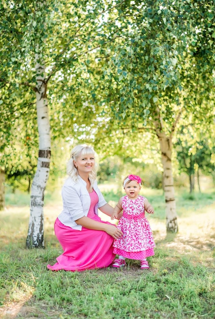 Linda mãe brincando com o bebê na natureza no verão