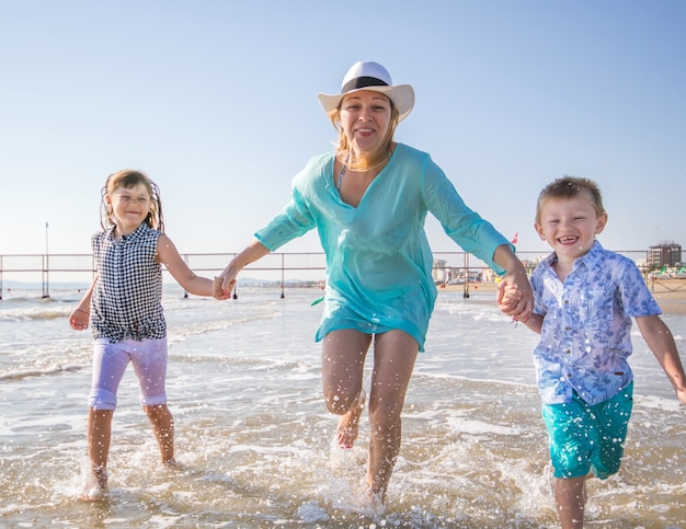 Linda mãe brincando com seus filhos no mar