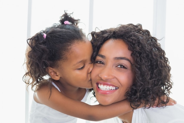 Foto linda mãe com a filha beijando sua bochecha