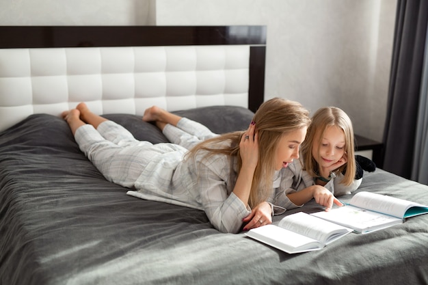 Linda mãe com filha de pijama sentada na cama