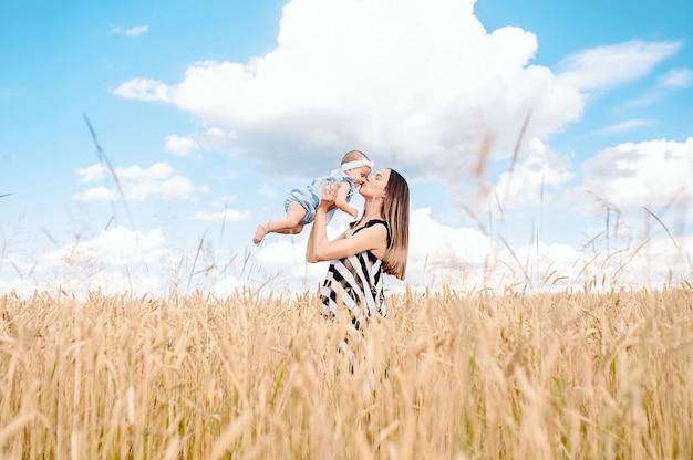 Linda mãe com seu bebê no campo de trigo