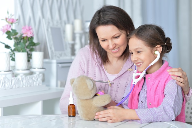 Linda mãe com sua filha brincando de enfermeira em casa