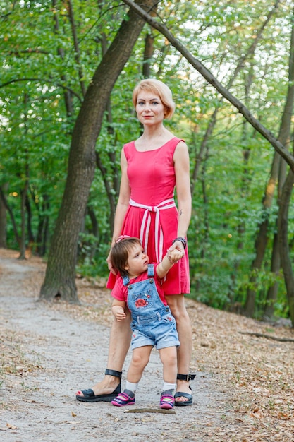 Linda mãe com sua filha caminha no parque no verão