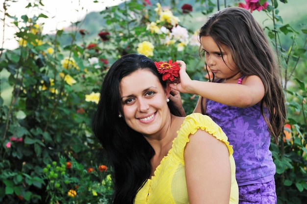 linda mãe e filha ao ar livre no jardim junto com flor se divertir e abraçar