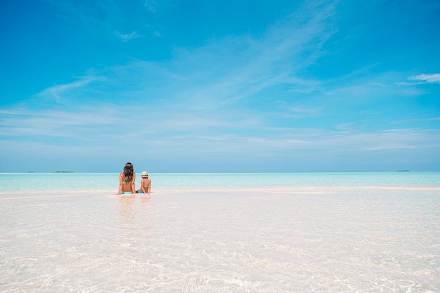 Linda mãe e filha na praia do caribe, aproveitando as férias de verão.